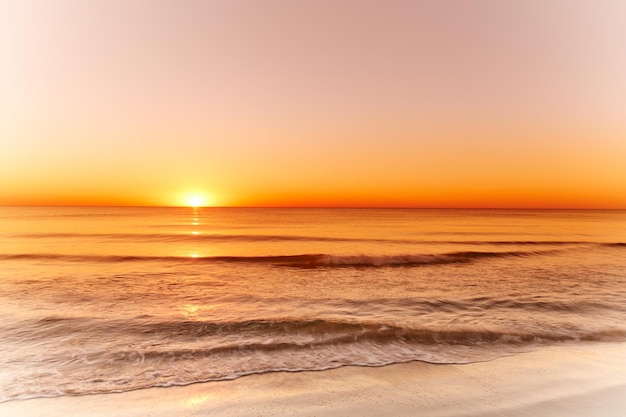 Landscape and sunset view of an empty beach or ocean at dusk in the evening Seascape with copy space of a golden sun setting over the horizon on the west coast of Jutland in Loekken Denmark