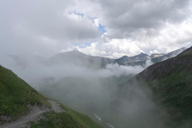 Пейзажный вид на Альпы. Вершины покрыты облаками и туманом из-за штормовой погоды.