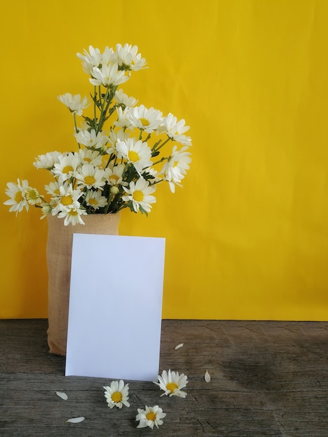 Photo landscape view of brown  jug with fresh cut daisies on yellow background and note space fo