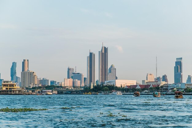 Photo landscape view of buildings at the chao phraya riverside and boats in the river bangkok thailand