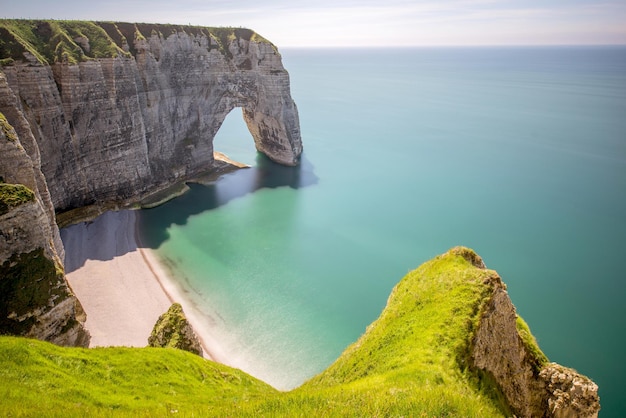 Landscape view on the famous rocky coastline near Etretat town in France during the sunny day. Long exposure image technic with soft water