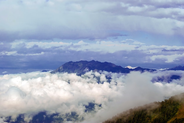 Пейзаж - вид с горного перевала в солнечный день на долину, скрытую низкими облаками.