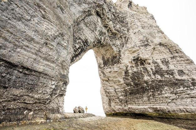 Landscape view on the huge stone cliff with a hole and traveler standing inside