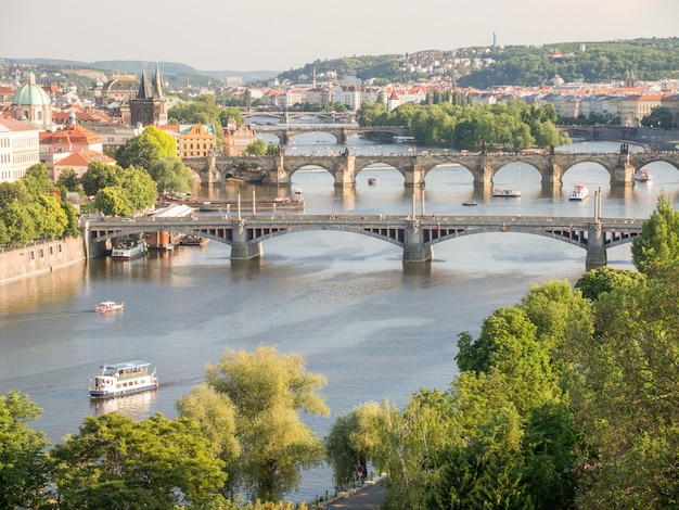 Landscape of the Vltava River with bridges over it surrounded by greenery and buildings in Prague