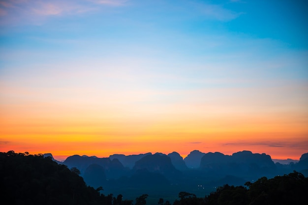 Landscape with beautiful dramatic sunset and silhouette of blue mountains at horizon, Thailand