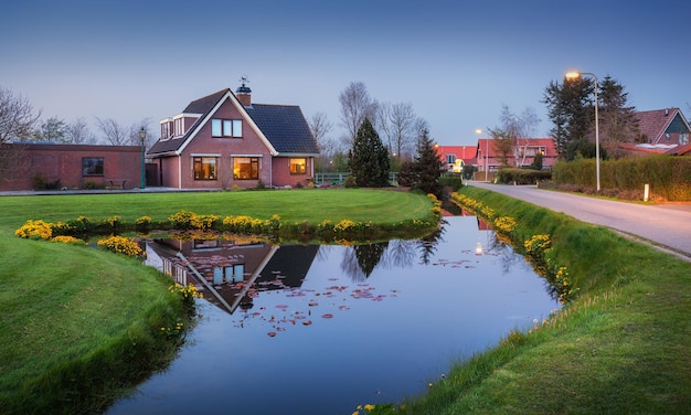 Landscape with beautiful house reflected in water canal at dusk