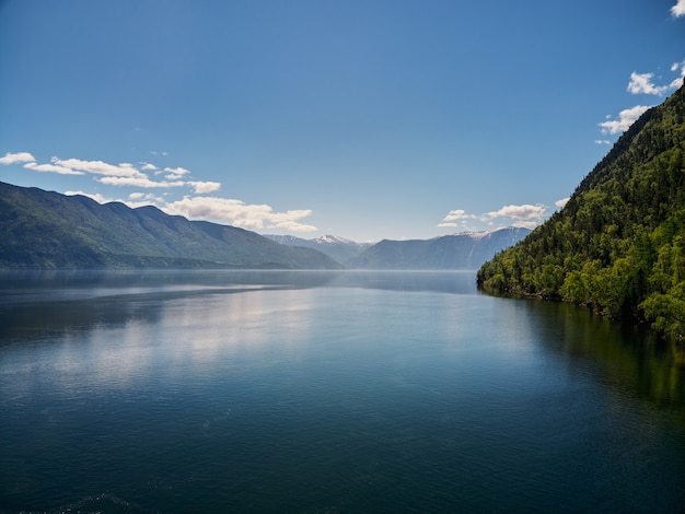 Landscape with boats in the water lake with views of the mountains. Teletskoye Lake Altai in Siberia.