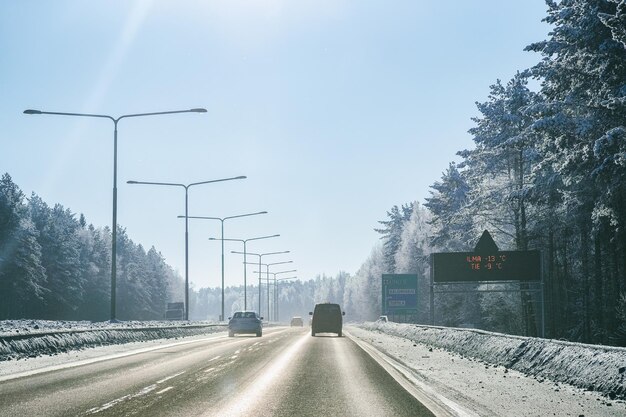 雪の降る冬のラップランド、ロヴァニエミ、フィンランドの道路で車のある風景