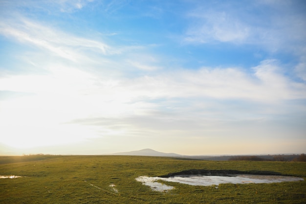 Landscape with green meadow and blue sky with clouds on sunset