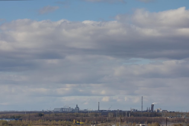 Paesaggio con impresa industriale all'orizzonte con un bel cielo nuvoloso