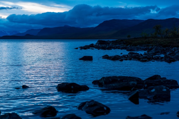 Landscape with lake and mountains with dramatic sky in background