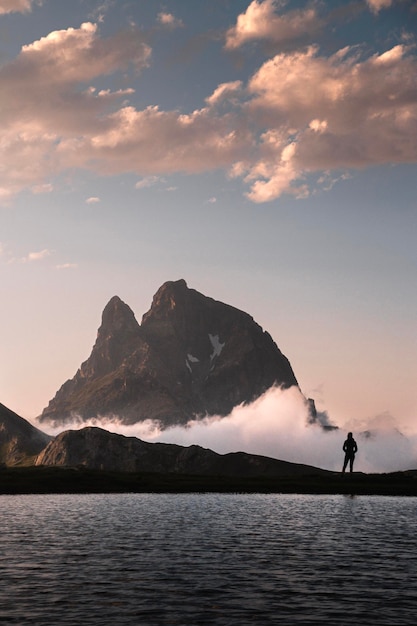 Photo landscape with the majestic midi d'ossau above clouds at sunset and a person enjoying the views