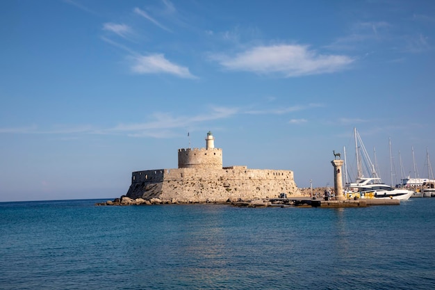 Photo landscape with mandraki harbour and two statues, elefos and elafina in rhodes island, greece