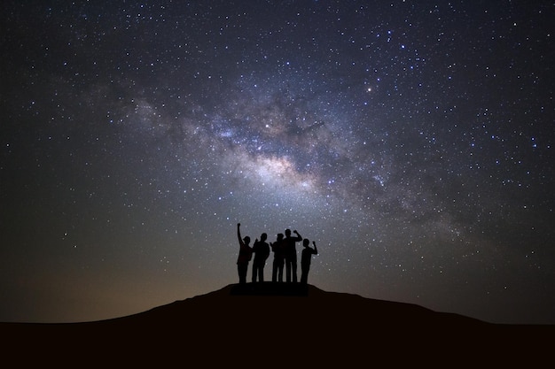 Landscape with milky way galaxy starry night sky with stars and\
silhouette of people standing