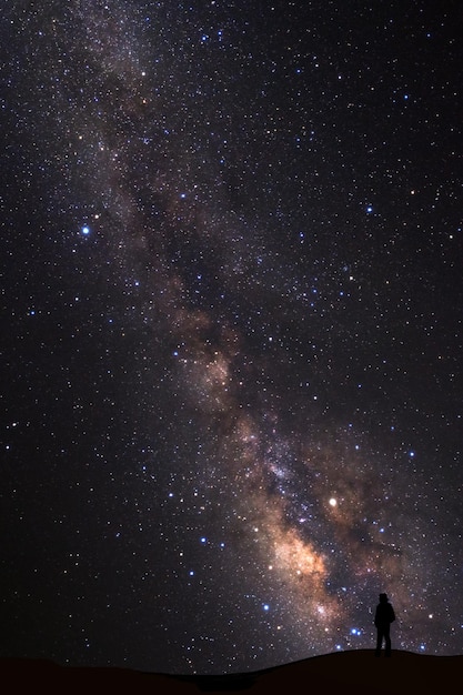 天の川のある風景 星のある夜空と高い山に立っている人のシルエット