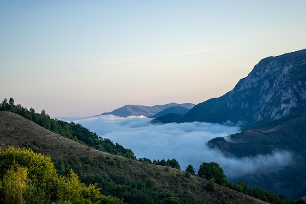 Landscape with mountains and clouds covering valley, scenic view in nature.