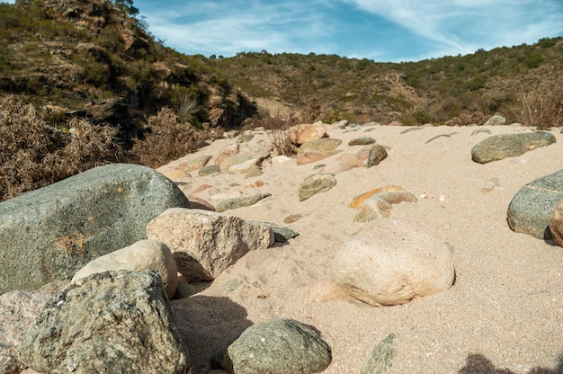 landscape with sandy soil stones mountains with vegetation and a beautiful blue sky with clouds