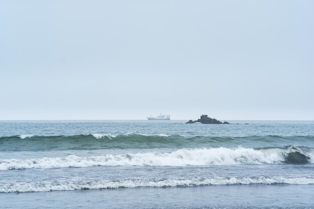 海の岩と遠くに帆船のある風景