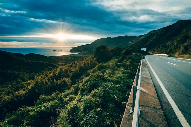 写真 海のある風景、雲のある晴れた空、夏の夕方の美しいアスファルト道路。