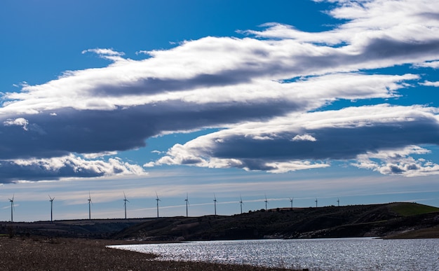 A landscape with windmills and a cloudy sky