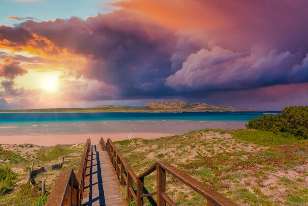 Landscape of wooden footbridge to the sea at dramatic sunset
