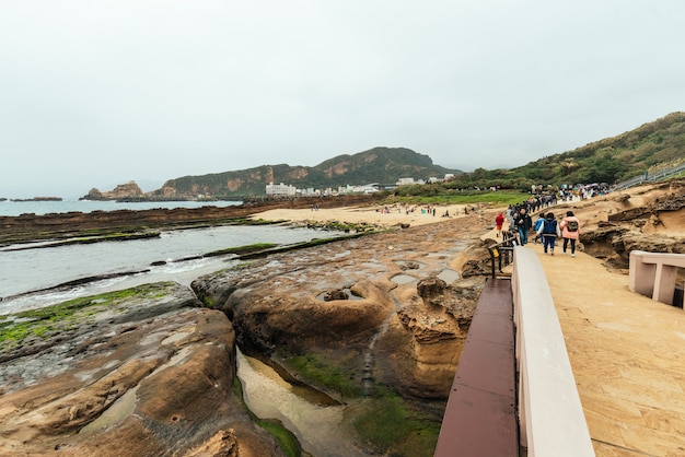 Landscape of Yehliu Geopark, a cape on the north coast of Taiwan. A landscape of honeycomb and mushroom rocks eroded by the sea with city buildings in the background.