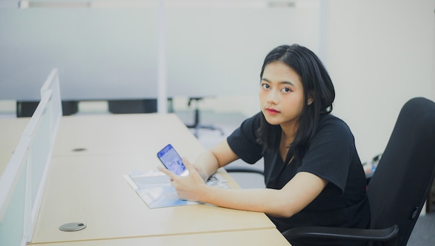 landscape of young female secretary with serious gaze while holding cellphone