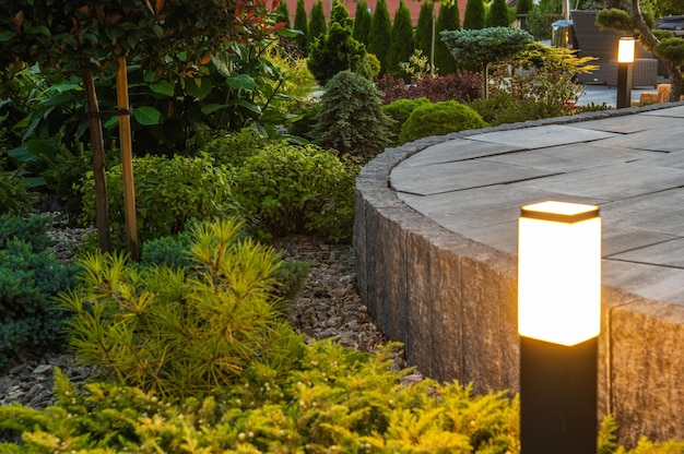 Landscaped backyard in the residential house beautiful and rich in various plants garden with large concrete porch surrounded by bollard outdoor lights