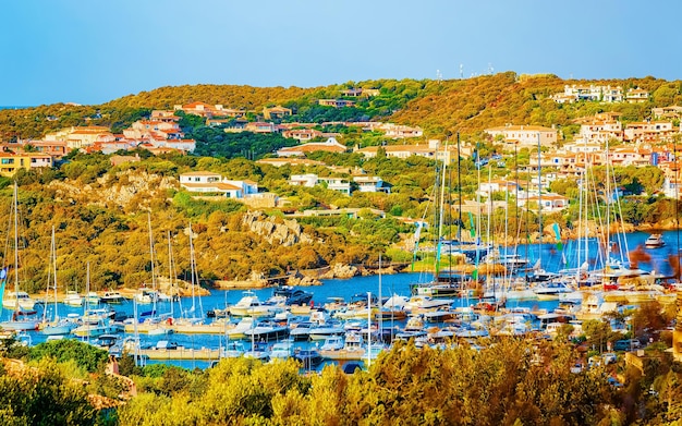 Landschap met jachthaven en luxe jachten aan de Middellandse Zee van Porto Cervo op het eiland Sardinië in Italië in de zomer. Landschapsmening over Sardijnse stadshaven met schepen en boten in Sardegna. Gemengde media.