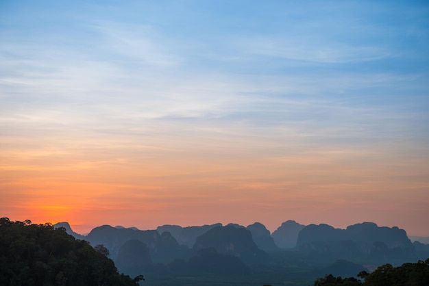 Landschap met prachtige dramatische zonsondergang en silhouet van blauwe bergen aan de horizon, Thailand