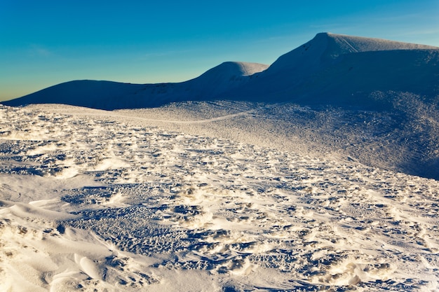 Landschap van bergdal bedekt met sneeuw op heldere ijzige winterdag