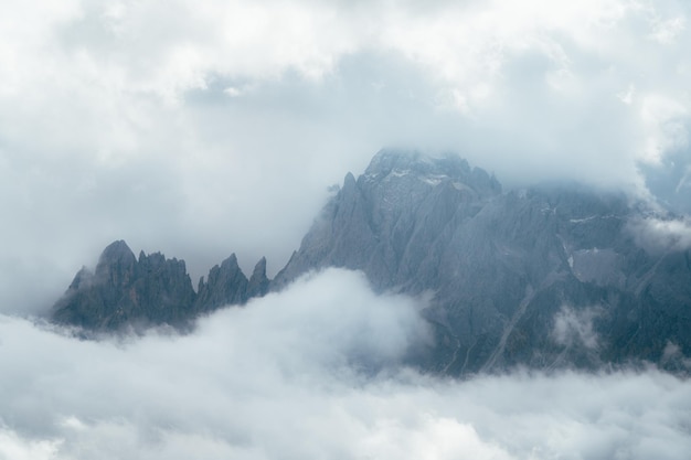 Landschap van de Dolomieten bergketen bedekt met mist onder een bewolkte hemel in Italië