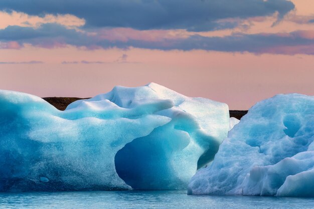 Landschap van de Jokulsarlon-gletsjerlagune met het smelten van blauwe ijsbergen en zonsonderganghemel op de zomer