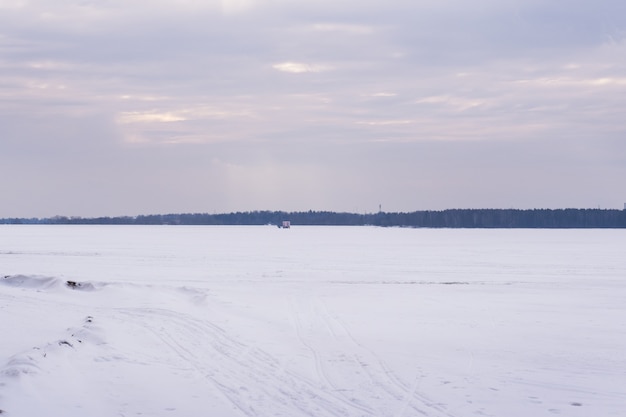 Landschap van een bevroren meer in de winter. Het wateroppervlak in het meer is bedekt met sneeuw en ijs.