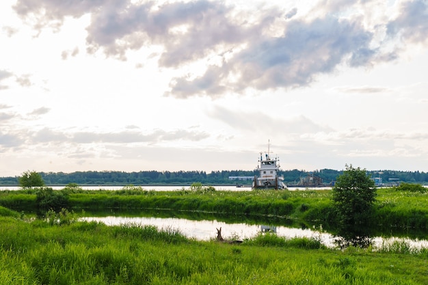 Landschap van een rivierdelta met een sleepboot en een baggerschip op de achtergrond