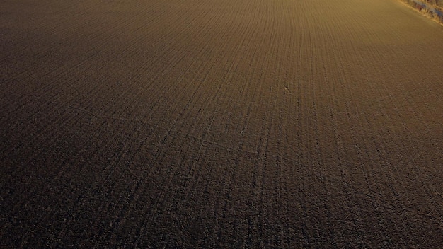 Landschap van geploegd land op een landbouwveld op een zonnige herfstdag vliegend over de geploegde ea