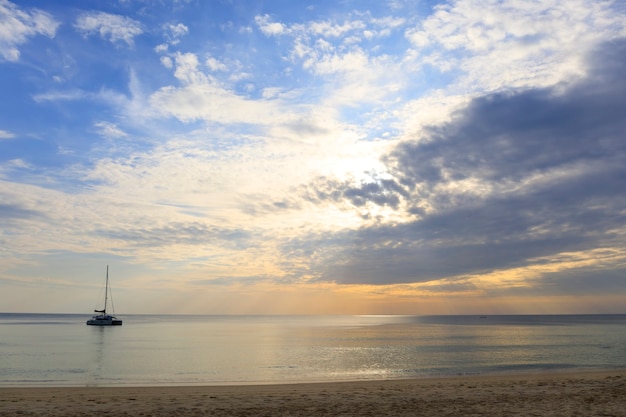 Landschap van heldere zee en wolken met de gouden stralen van de zon komen achter de wolken vandaan met een boot op zee.