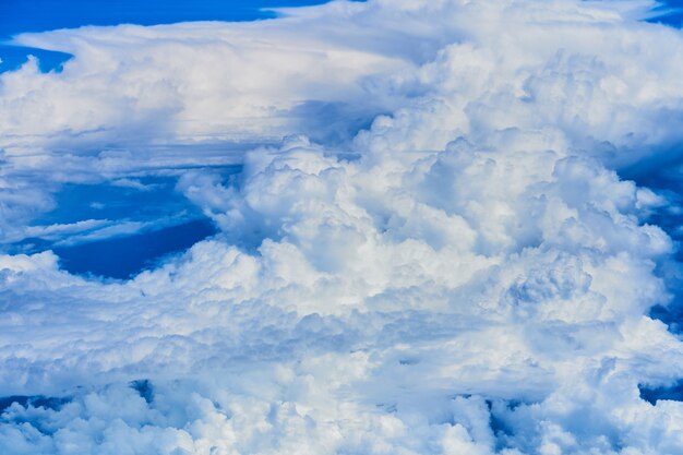 Landschap van pluizige witte wolken op een donkerblauwe hemel. Uitzicht vanuit het vliegtuig op grote hoogte.