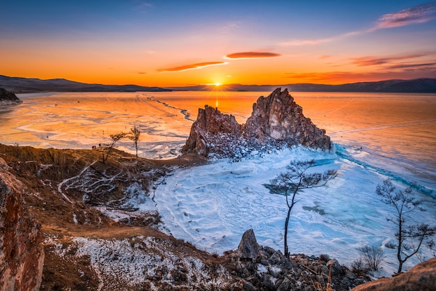 Landschap van shamanka-rots bij zonsondergang met natuurlijk brekend ijs in bevroren water op meer baikal, siberië, rusland.