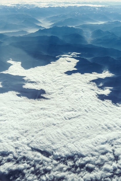 Landschapsmening van Alpiene bergen met wolken van het vliegtuig