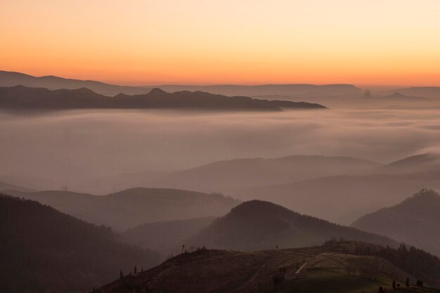 landschapsmening van mistige bergen onder zonsonderganglicht