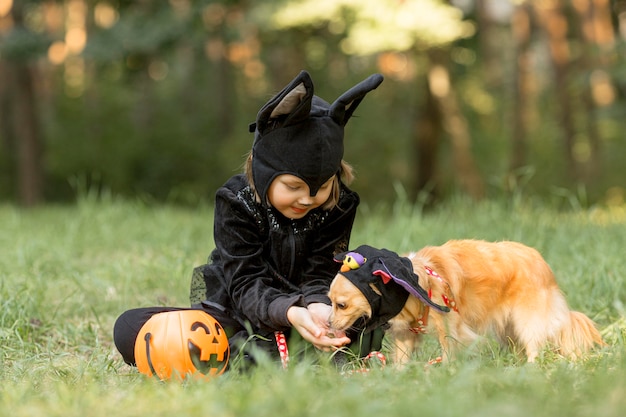 Foto lang schot van kleine jongen in vleermuiskostuum en hond