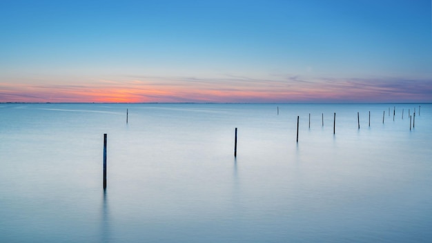 Foto lange blootstelling aan het ijsselmeer met een eindeloze horizon tijdens een atmosferische zonsondergang