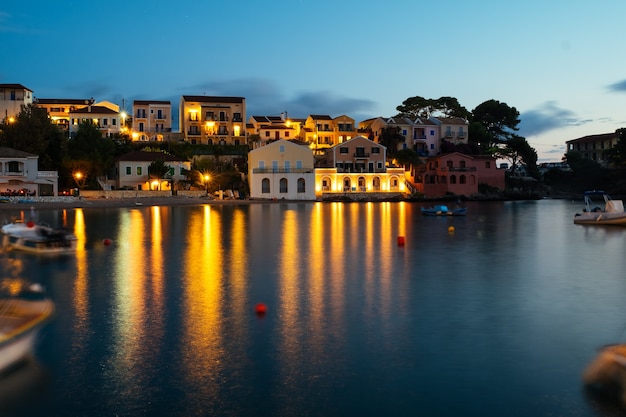 Lange blootstelling van de schattige oude stad aan de kust bij zonsondergang met boten in de baai.