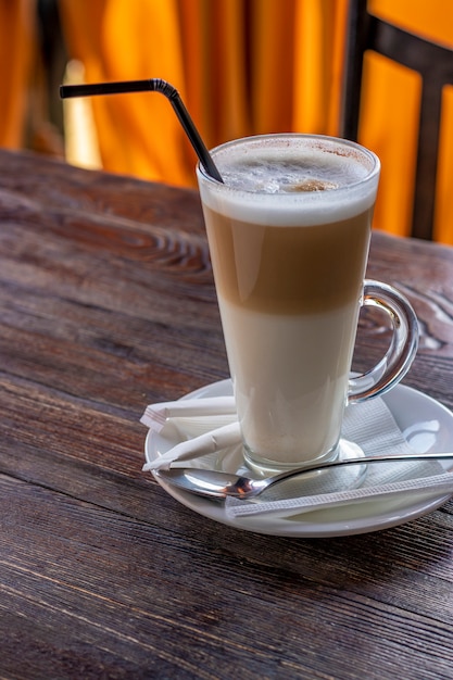 Lange glazen kopje koffie latte op houten tafel, verticaal formaat