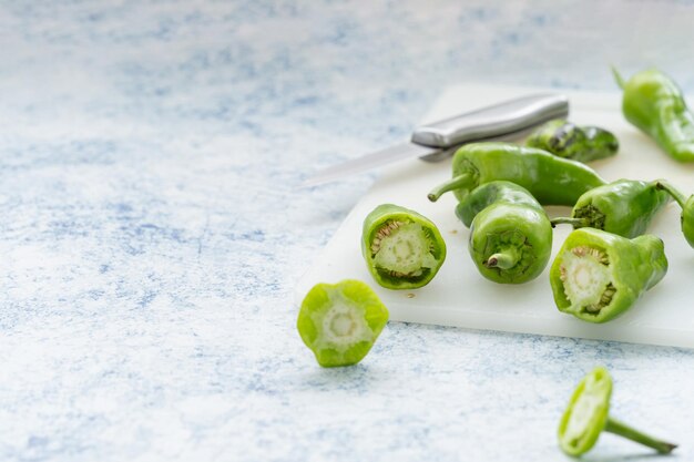 Foto lange groene paprika's van verschillende afmetingen gesneden op een snijplank met hun binnenste vol zaden