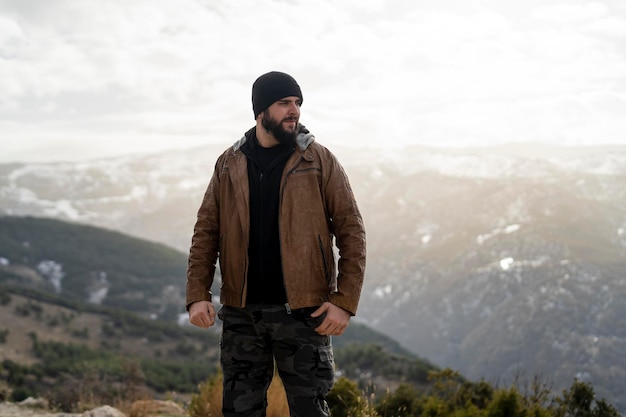 lange man met een baard op de berg die warme kleren draagt en poseert