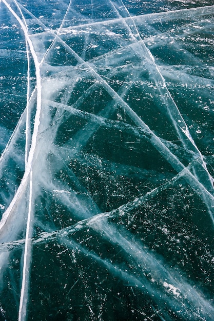 Lange scheuren op het transparante ijs van het Baikalmeer. Veel scheuren in dik ijs. Verticale oriëntatie.