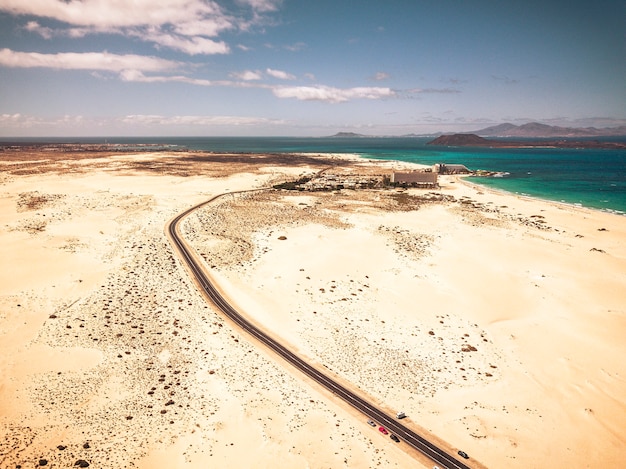 Lange snelweg asfaltweg met woestijn en zandstrand aan beide kanten - hoge luchtfoto met oceaan en eilanden