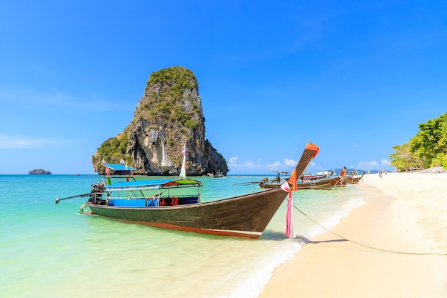 Lange staartboot en turkoois kristalhelder zeewater met kalkstenen klif en berg bij Phra Nang Beach, Krabi, Thailand